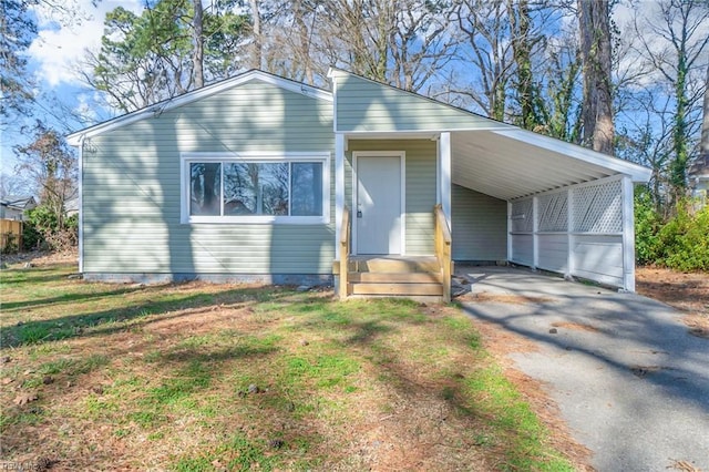 view of front of property with aphalt driveway, an attached carport, entry steps, and a front yard