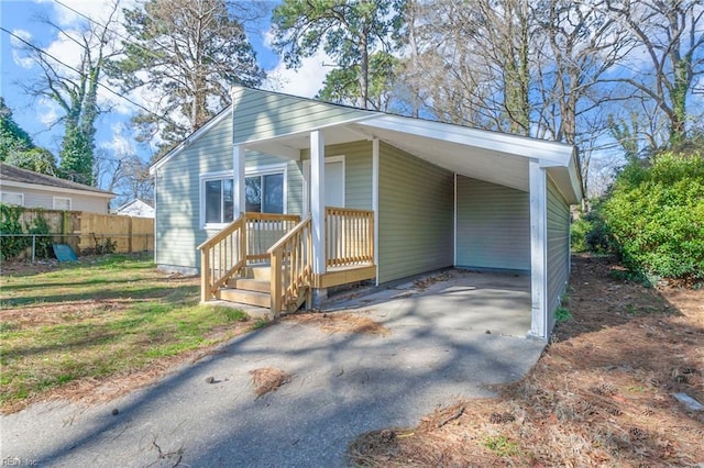 view of front facade with a carport, driveway, and fence