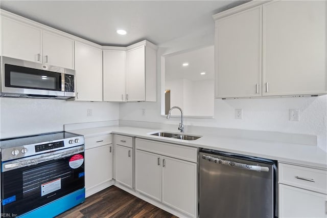 kitchen with a sink, stainless steel appliances, light countertops, dark wood-type flooring, and white cabinetry