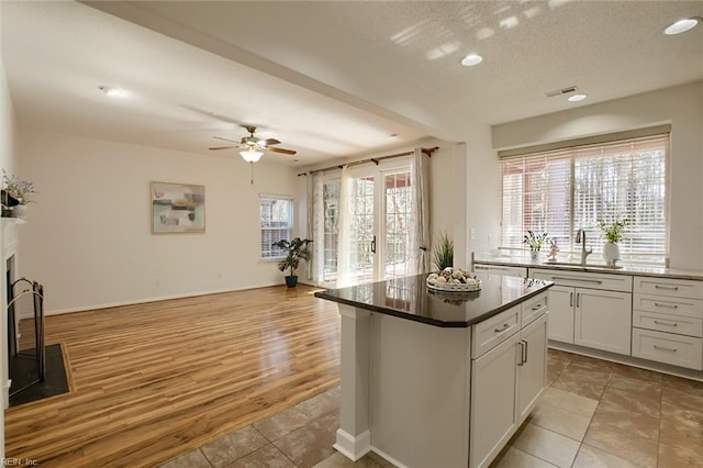 kitchen featuring visible vents, a kitchen island, ceiling fan, open floor plan, and a sink