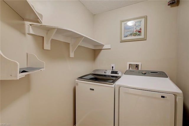 laundry room featuring separate washer and dryer, laundry area, and a textured ceiling