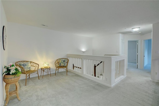 sitting room featuring an upstairs landing, visible vents, baseboards, and carpet floors