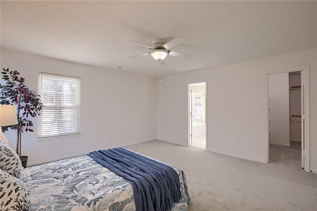 bedroom featuring light colored carpet, baseboards, ensuite bathroom, and ceiling fan