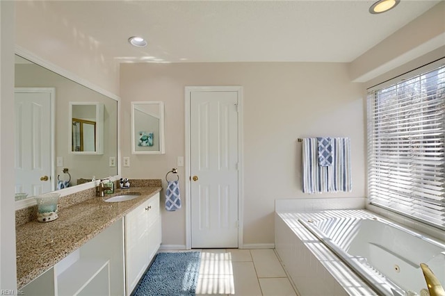 bathroom featuring tile patterned flooring, vanity, tiled bath, and baseboards