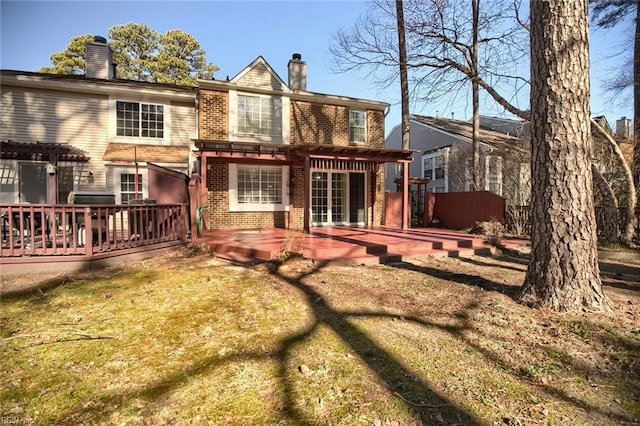 back of property featuring a pergola, a wooden deck, brick siding, and a chimney