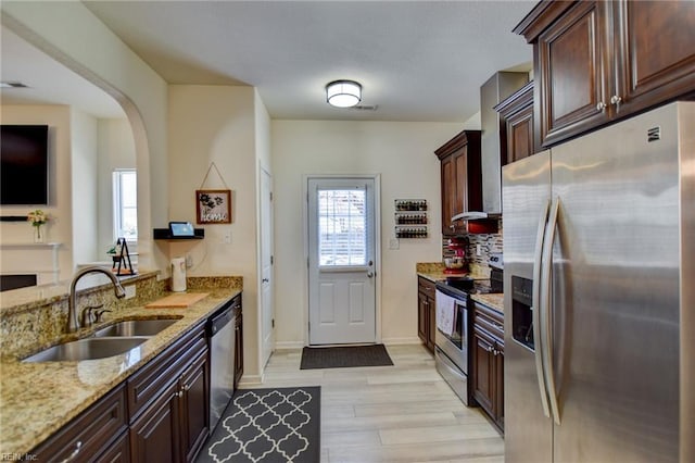 kitchen featuring a sink, dark brown cabinetry, light stone countertops, and stainless steel appliances