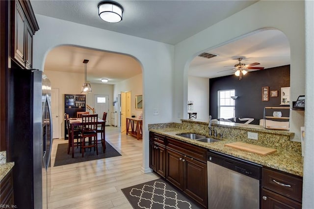 kitchen with light wood-style flooring, arched walkways, stainless steel appliances, a ceiling fan, and a sink