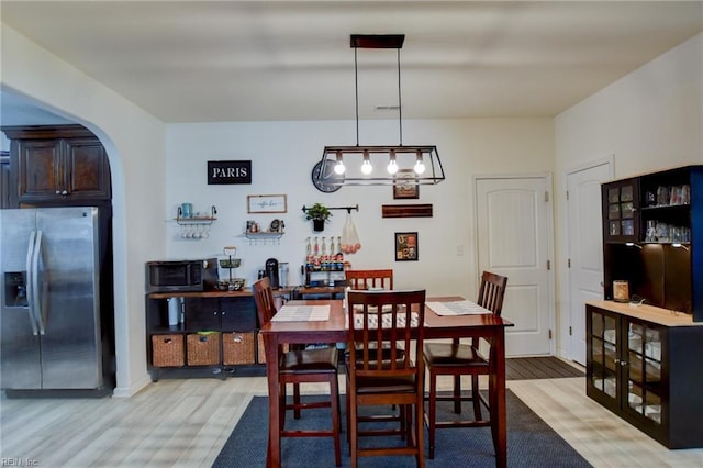 dining room with arched walkways and light wood finished floors