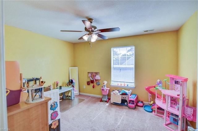 game room with carpet, a ceiling fan, visible vents, baseboards, and a textured ceiling