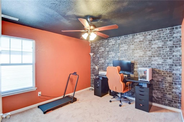 carpeted home office with baseboards, visible vents, brick wall, ceiling fan, and a textured ceiling