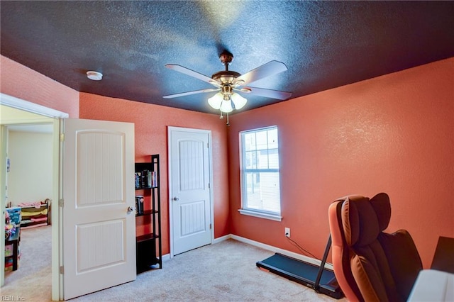 home office featuring ceiling fan, a textured ceiling, a textured wall, and light carpet