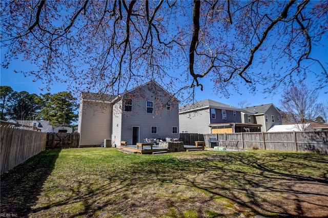 rear view of property featuring cooling unit, a lawn, and a fenced backyard