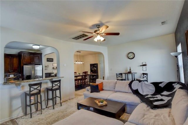 living area featuring arched walkways, visible vents, baseboards, and ceiling fan