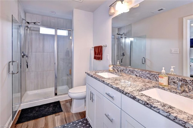 bathroom featuring toilet, visible vents, a stall shower, and a sink