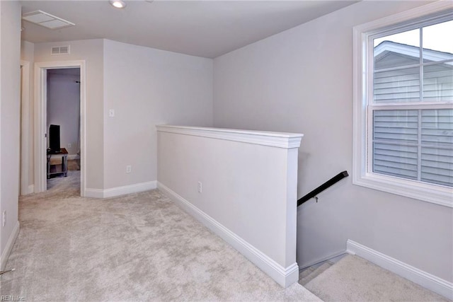 hall with visible vents, an upstairs landing, baseboards, and carpet floors