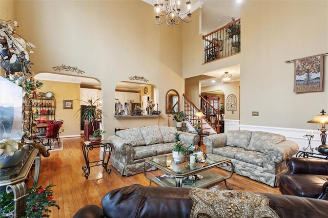 living area with stairway, arched walkways, hardwood / wood-style flooring, wainscoting, and a chandelier