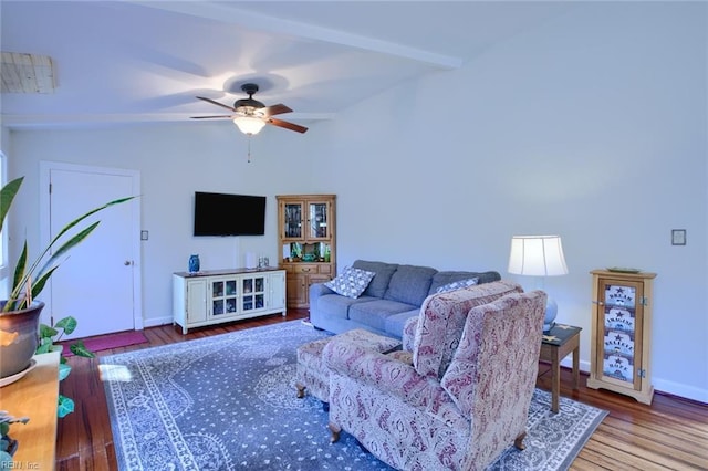 living room featuring ceiling fan, vaulted ceiling with beams, baseboards, and wood finished floors