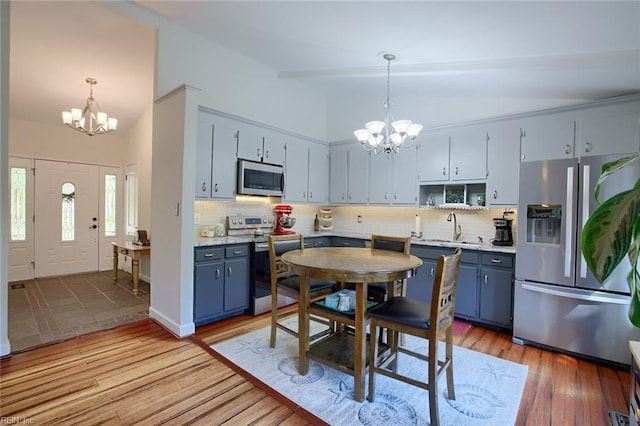 kitchen featuring a sink, stainless steel appliances, blue cabinetry, and a notable chandelier