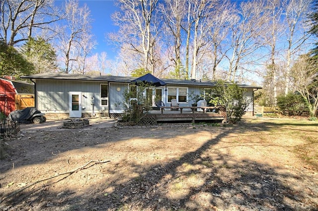 rear view of house with a deck and an outdoor fire pit