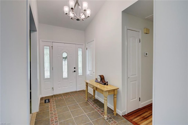 foyer entrance with tile patterned floors, baseboards, and an inviting chandelier