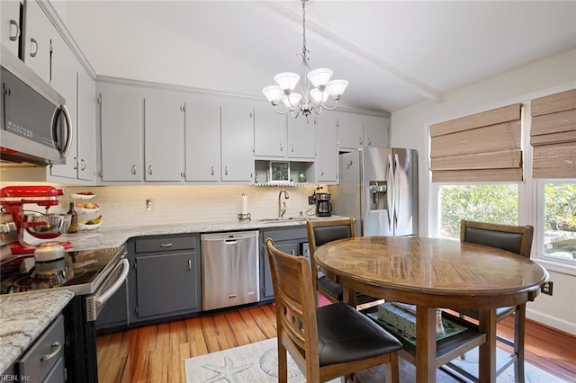 kitchen featuring light wood-style flooring, a sink, gray cabinetry, stainless steel appliances, and a chandelier