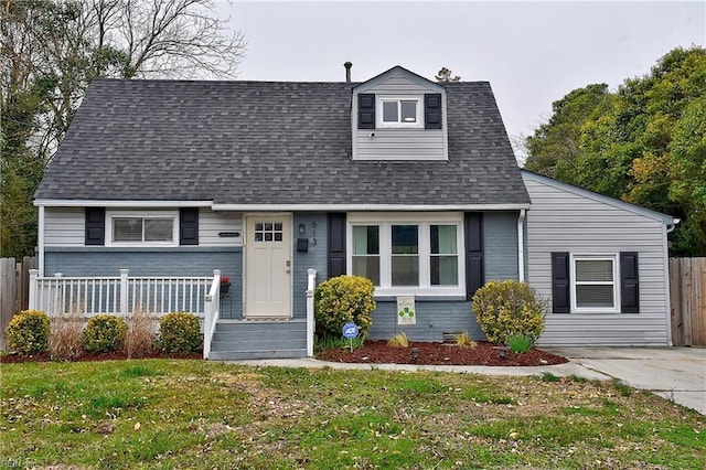 view of front facade featuring a shingled roof, a front yard, and fence