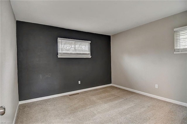 unfurnished room featuring visible vents, plenty of natural light, carpet, and baseboards