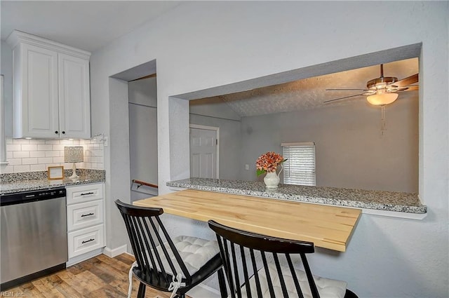 kitchen featuring wood finished floors, white cabinetry, decorative backsplash, lofted ceiling, and dishwasher