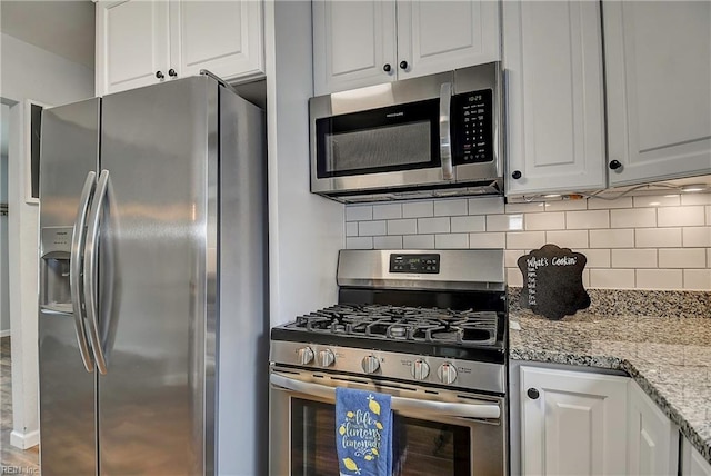 kitchen featuring decorative backsplash, appliances with stainless steel finishes, and white cabinetry