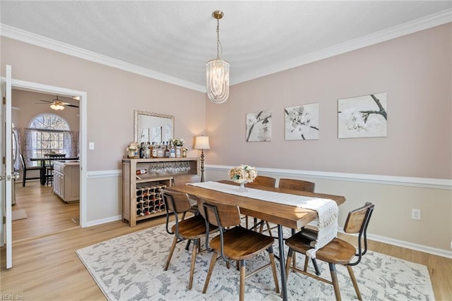 dining room with ornamental molding, baseboards, and light wood finished floors