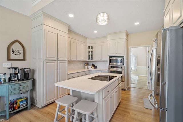 kitchen featuring light countertops, a kitchen bar, a center island, stainless steel appliances, and light wood-style floors