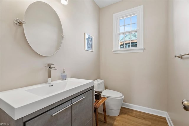 bathroom featuring toilet, vanity, baseboards, and wood finished floors