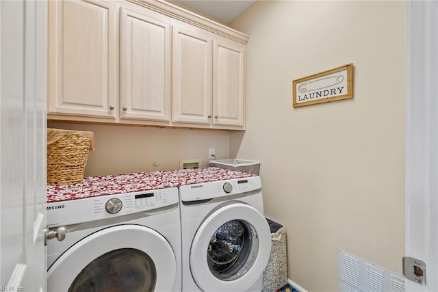 laundry area with visible vents, washing machine and clothes dryer, and cabinet space