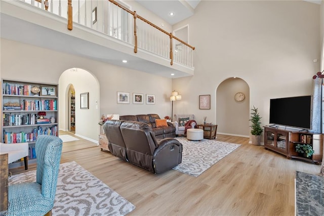 living area featuring arched walkways, baseboards, and wood finished floors