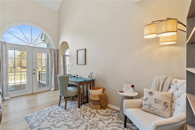 interior space with visible vents, baseboards, a towering ceiling, wood finished floors, and french doors