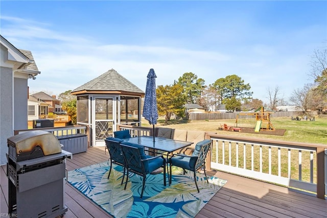 wooden terrace with area for grilling, a playground, outdoor dining area, a gazebo, and a lawn