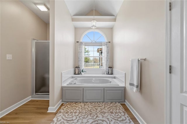 bathroom with lofted ceiling, baseboards, a shower stall, a garden tub, and wood finished floors
