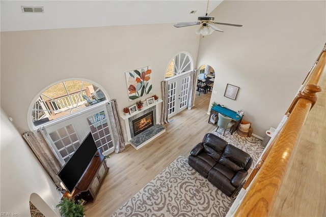 living room with high vaulted ceiling, ceiling fan, visible vents, a fireplace, and wood finished floors