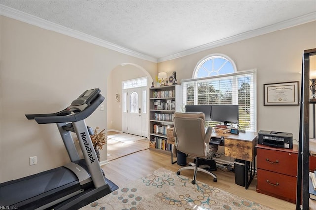 office space featuring wood finished floors, arched walkways, a textured ceiling, and a wealth of natural light
