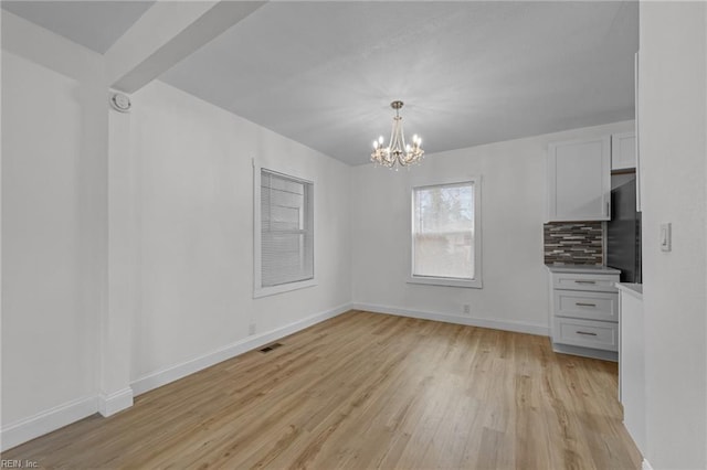 unfurnished dining area with light wood-type flooring, baseboards, a notable chandelier, and visible vents