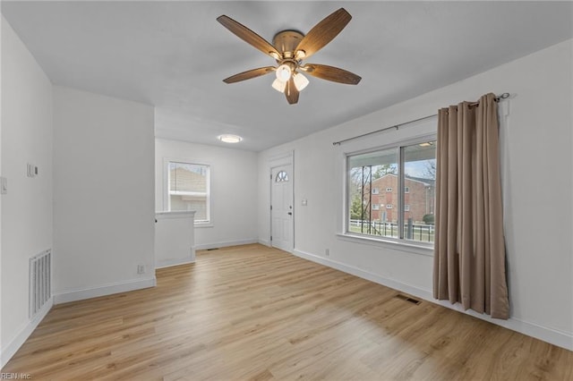 empty room featuring light wood-style flooring, baseboards, visible vents, and ceiling fan