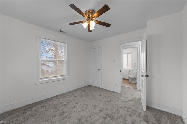 unfurnished bedroom featuring multiple windows, carpet, visible vents, and baseboards