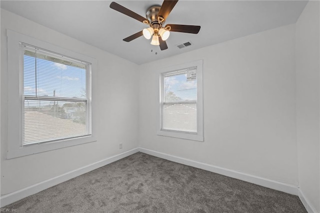 carpeted spare room featuring visible vents, a ceiling fan, and baseboards