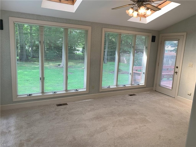 interior space with visible vents, a ceiling fan, vaulted ceiling with skylight, light colored carpet, and a textured wall