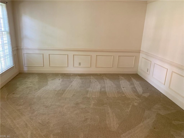 unfurnished room featuring a decorative wall and light carpet