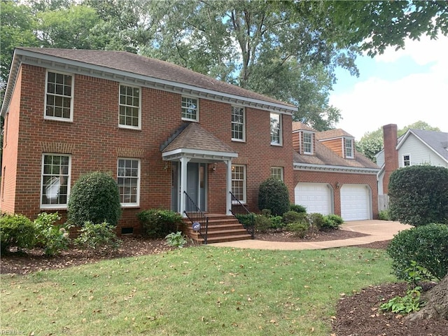 colonial house with brick siding, concrete driveway, a garage, and a shingled roof