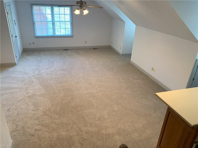 additional living space with light colored carpet, baseboards, a ceiling fan, and vaulted ceiling