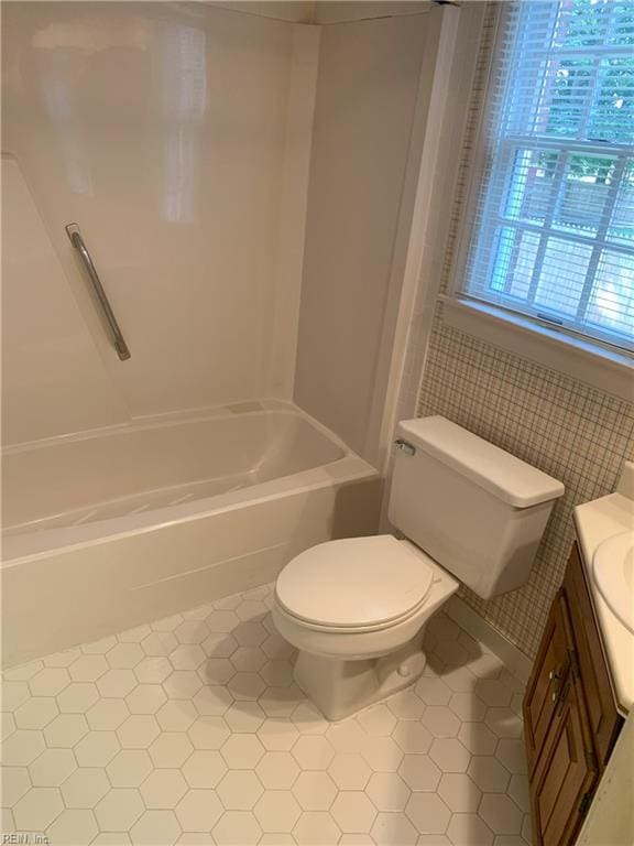 bathroom with tile patterned floors, toilet, vanity, and  shower combination