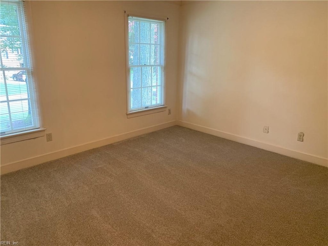 carpeted empty room featuring a healthy amount of sunlight and baseboards