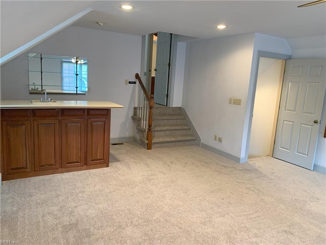 basement featuring stairs, recessed lighting, light colored carpet, and a sink